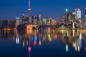 Stunning night view of Toronto skyline reflecting on water with CN Tower prominent.